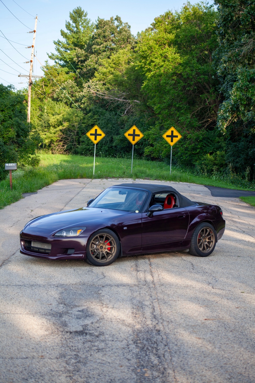 Portrait view of the purple Honda S2000 on a tree-lined road